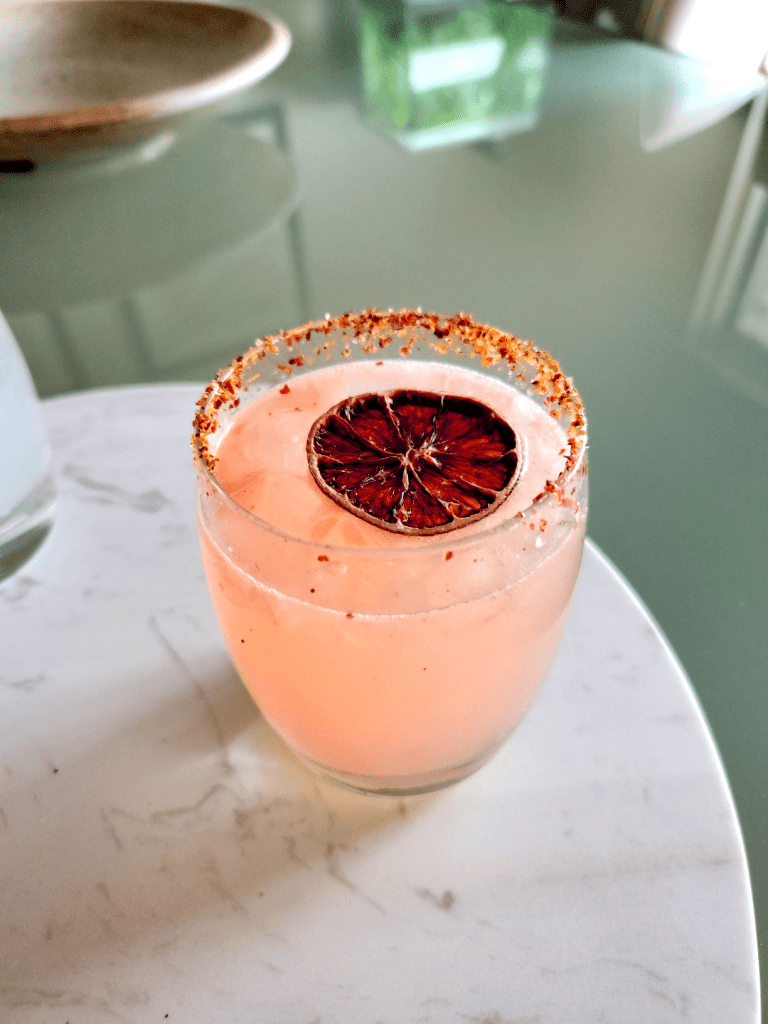 Picture of a Paloma the author made at home. It's a pink cocktail garnished with an intensely colored grapefruit wheel.