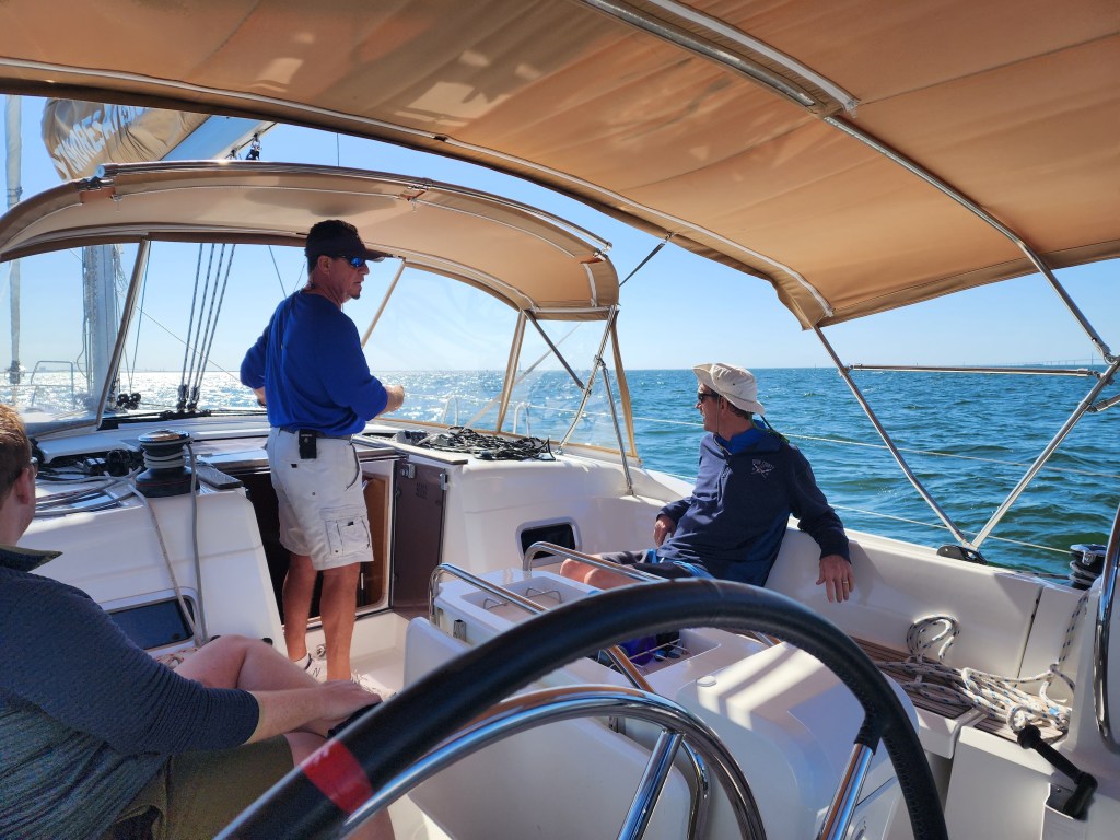 A picture of the cockpit of the boat, with the captain standing in the companionway, giving instructions as we're underway.