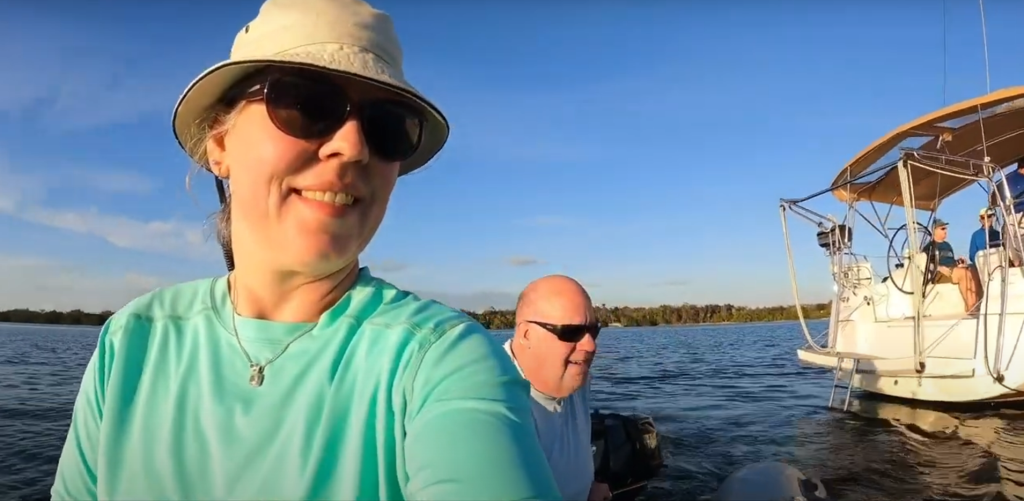 Kent and Becca riding the dinghy with the sailboat in the background.