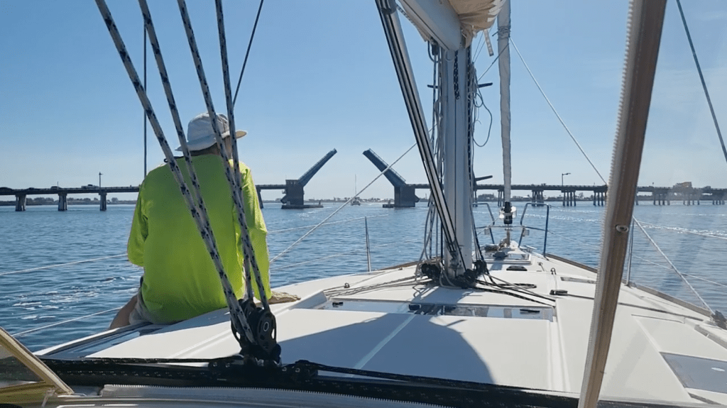 Joe sitting on the bow of the boat, with the Anna Maria drawbridge opening in the background.