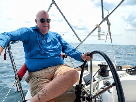 Kent sitting at the helm with his hand on the wheel