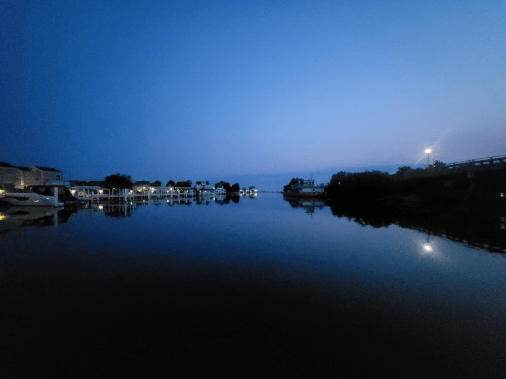 A marina at night, lit with lights from the boats