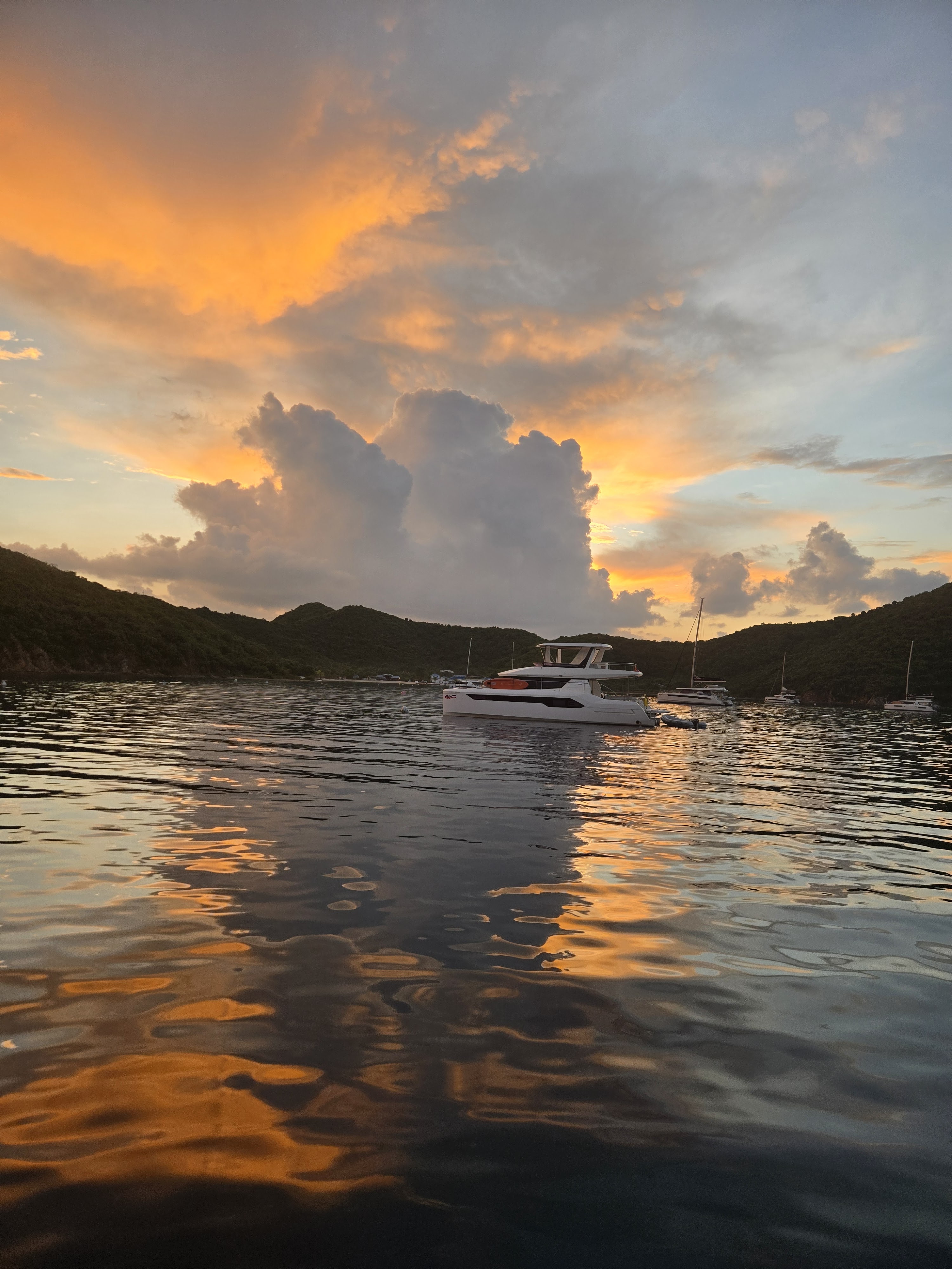 a stunning orange sunset behind an ocean bay, with a catamaran in the foreground