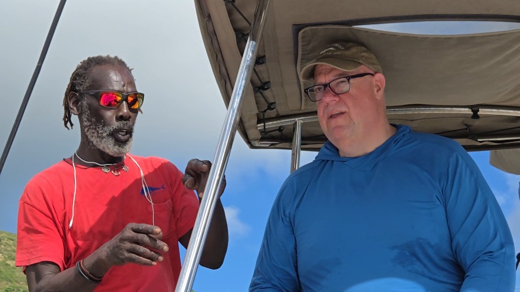 two men in the cockpit of the sailing catamaran