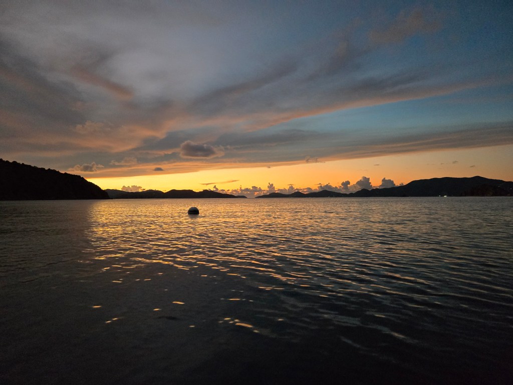 The sunset over the ocean, with a mooring ball in the foreground