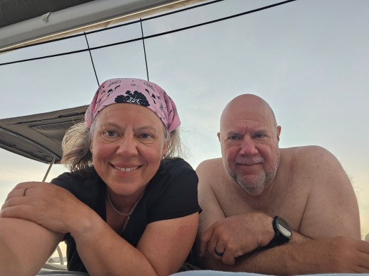 Two skippers lounging and smiling from the deck of a catamaran