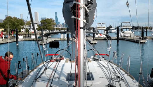 A man on a dock, preparing the lines on the deck of a sailboat