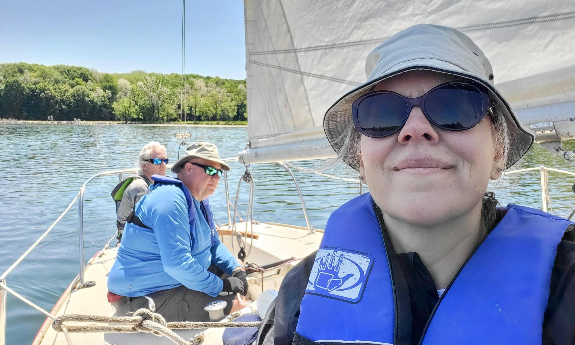 three passengers on a sailboat on a sunny day