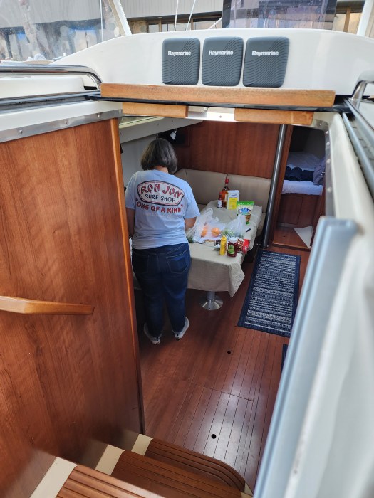 woman putting grocery items away in the galley of a sailboat