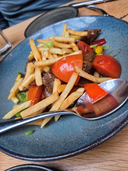 A plate full of beef stir-fry and french fries.