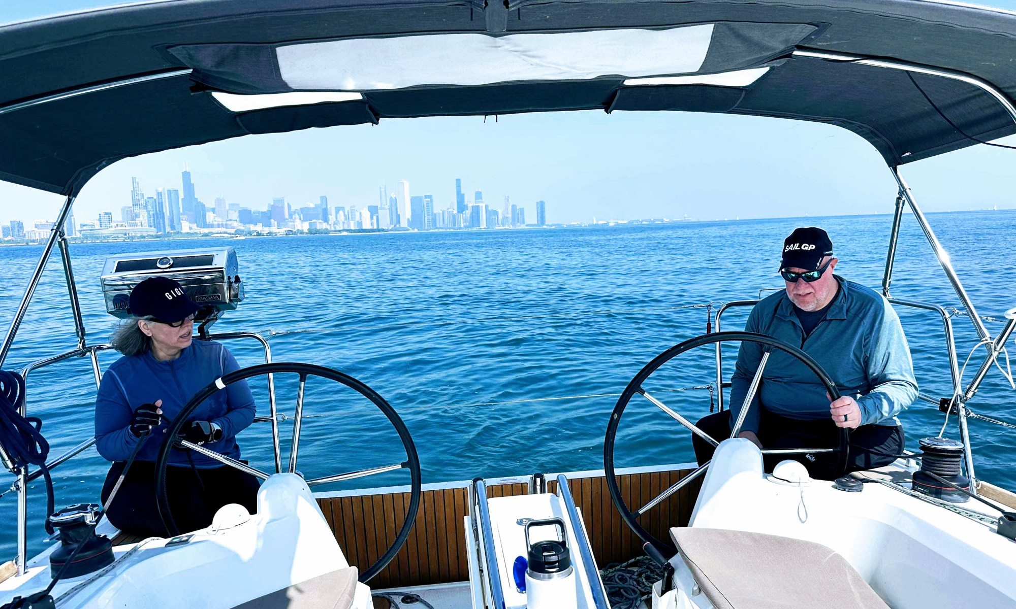 Kent and Becca sitting behind the wheels of a double-helm sailboat.
