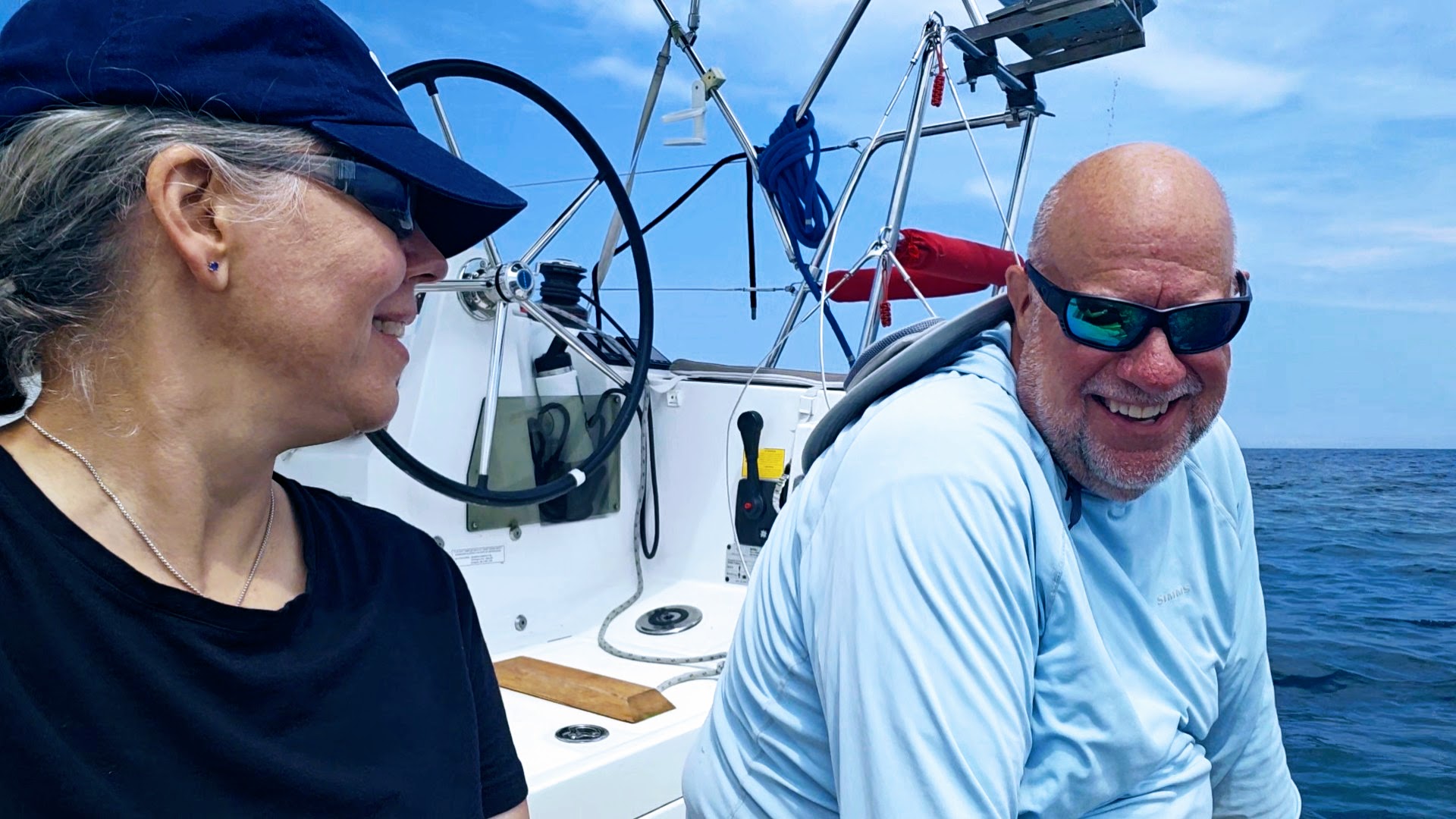 Kent and Becca sitting on the swim platform on the stern of Red Sky celebrating their successful heave to.