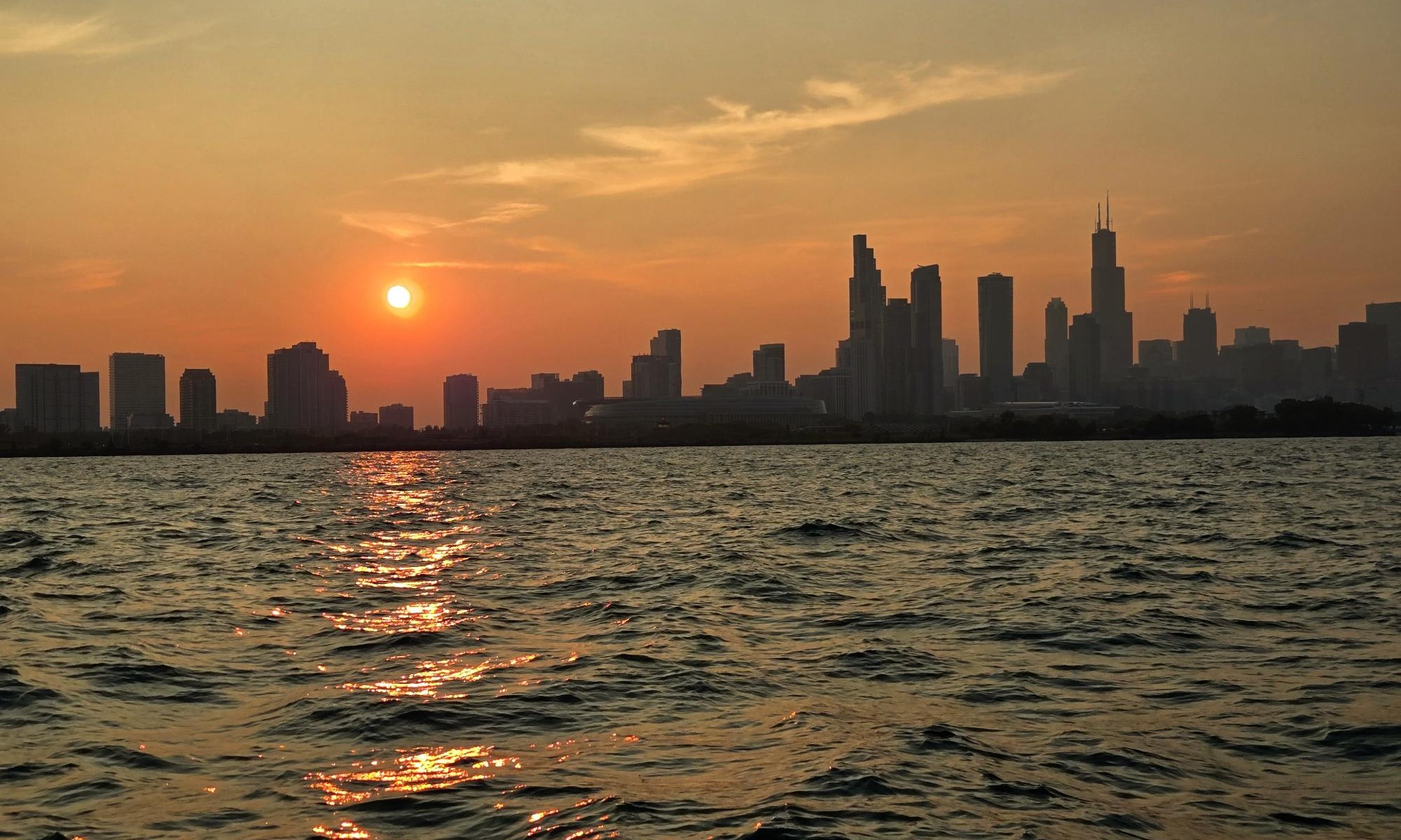 the sun is setting over the Chicago skyline.