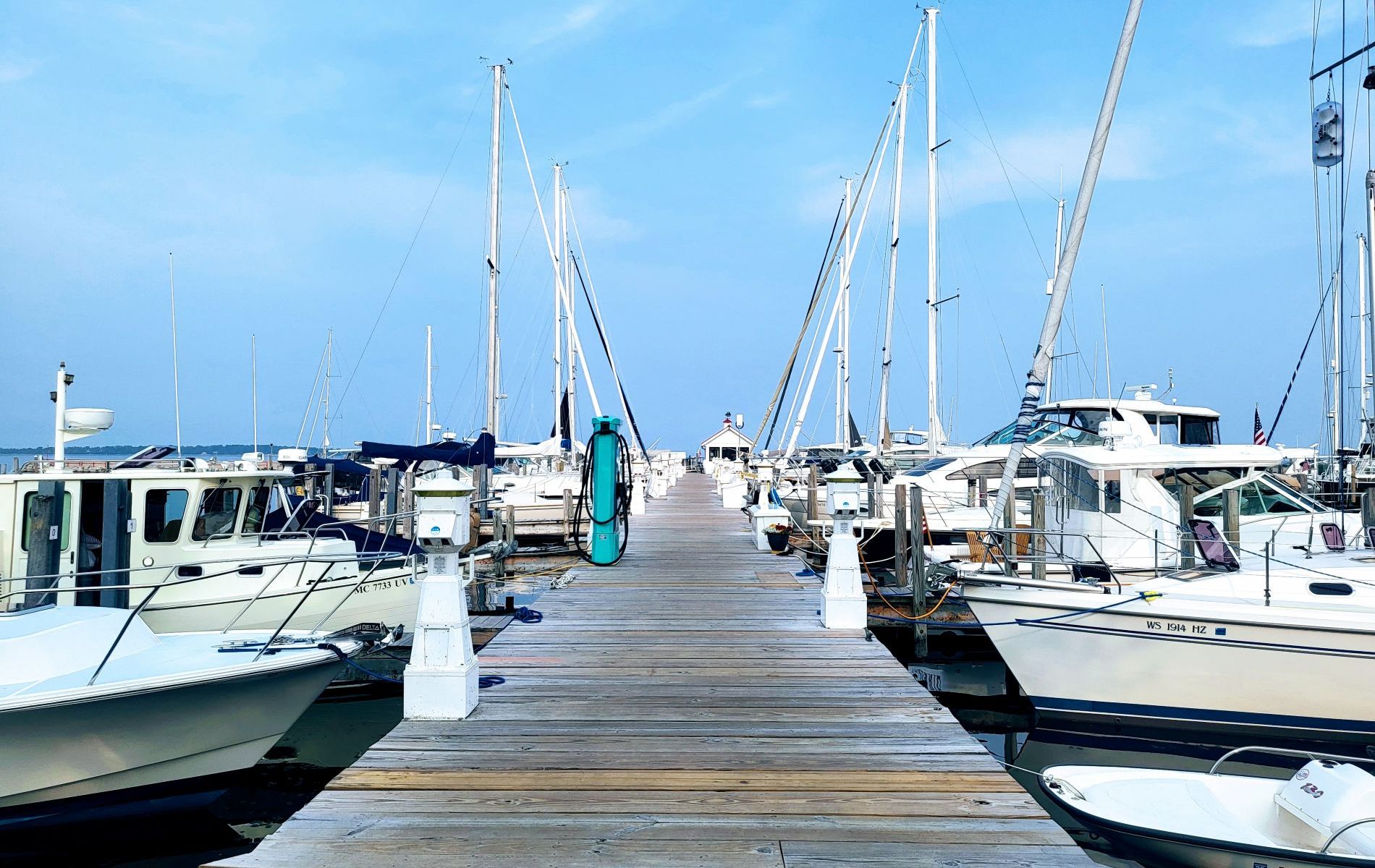 a wooden dock with boats on either side. cloudy skies overhead.