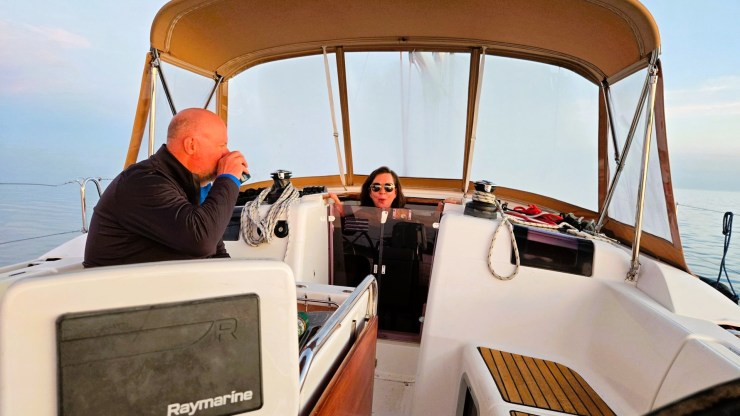 A Kent and Maria relaxing in the cockpit of a white sailboat.